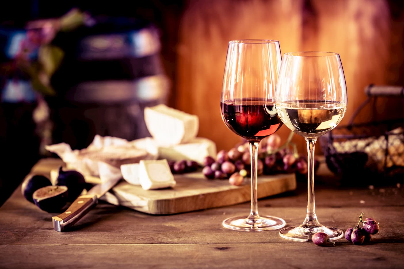 Rotwein und Weißwein im Glas vor Käseplatte